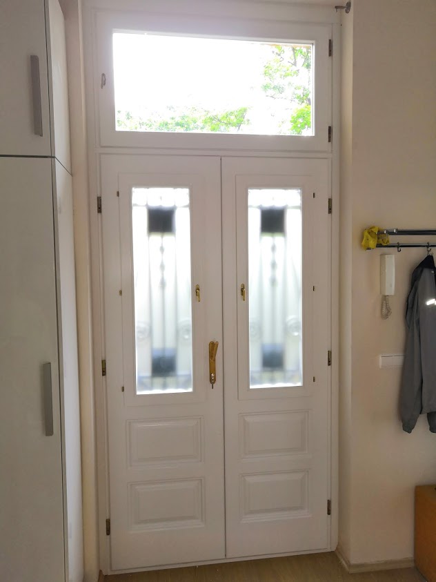 Társasház bejárati ajtó kovácsoltvas díszítéssel és üvegbetéttel