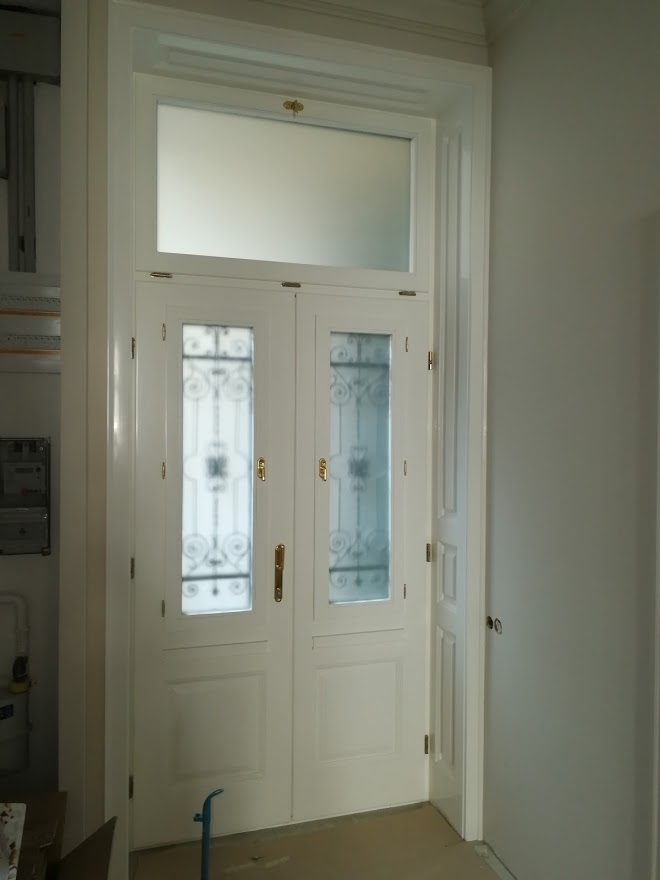Társasház bejárati ajtó kovácsoltvas díszítéssel és óvegbetéttel