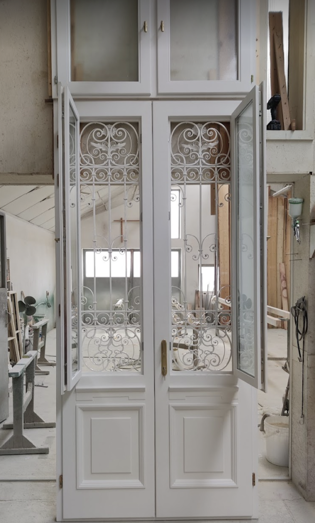 Budapesti műemléki társasház kétszárnyas bejárati ajtó kovácsoltvas díszítéssel